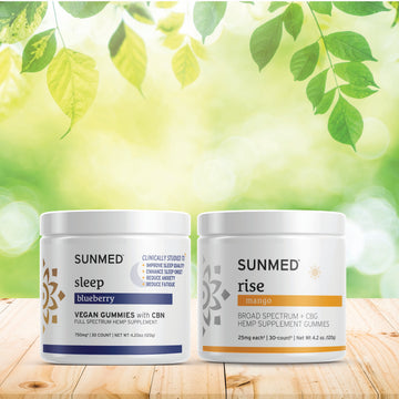 The Sunmed CBD Full Spectrum Sleep + Rise Gummies Bundle rests on a wooden surface outdoors—perfect for supporting your day and night routines.