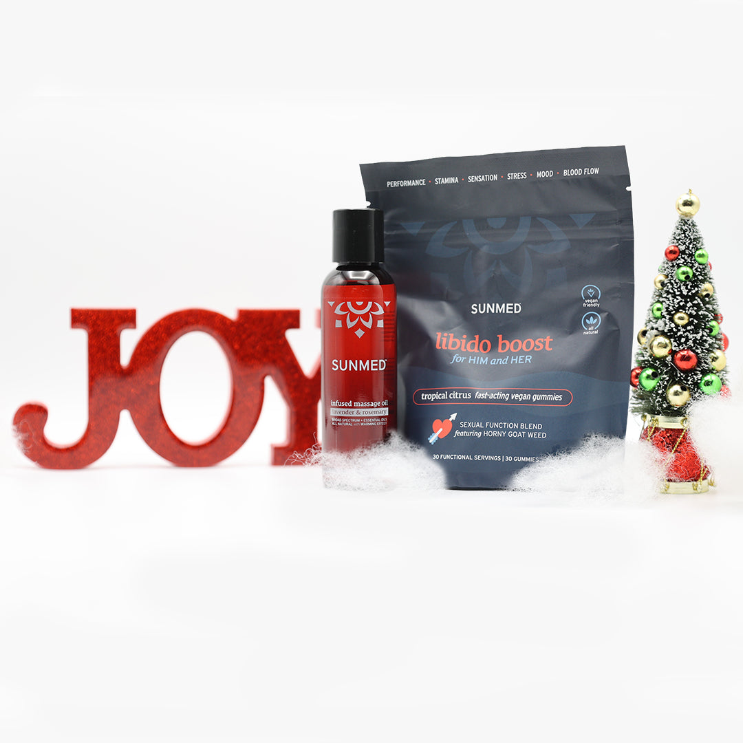 Sunmed CBD Libido Gummies + Massage Oil Bundle displayed with a festive Christmas tree and red JOY sign on snowy décor, perfect for holiday self-care and celebrating the season.