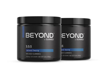 Sure! Here’s a rewritten sentence using the provided product data: Two jars of *20% Off* - 1:1:1 Indica Gummies 2-Pack by Sunmed CBD, featuring black containers with blue labels.