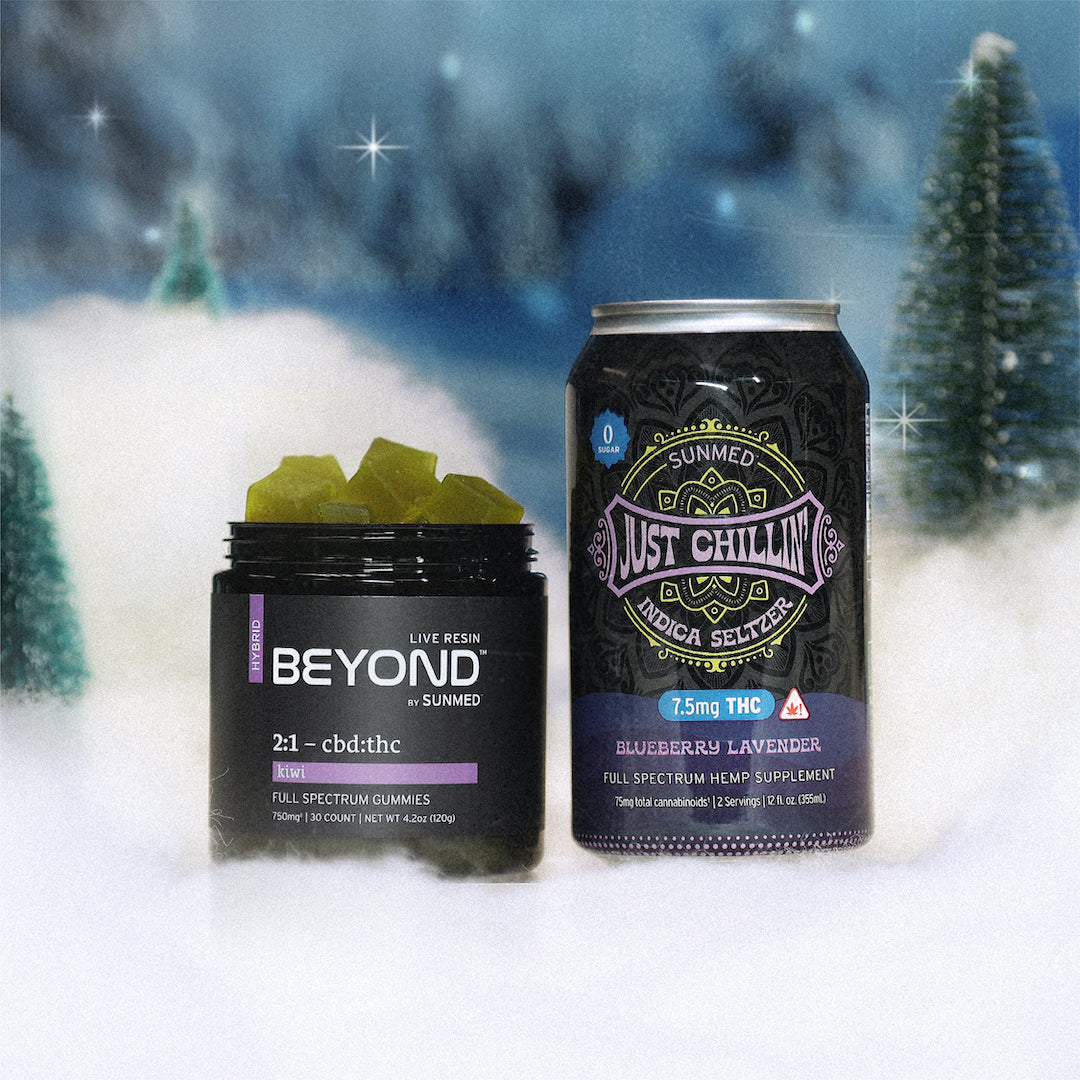 The BEYOND Hybrid Gummies and Just Chillin' Seltzer, part of the Holiday Bundle from Sunmed CBD, are placed on a snowy surface with blurred trees in the background.