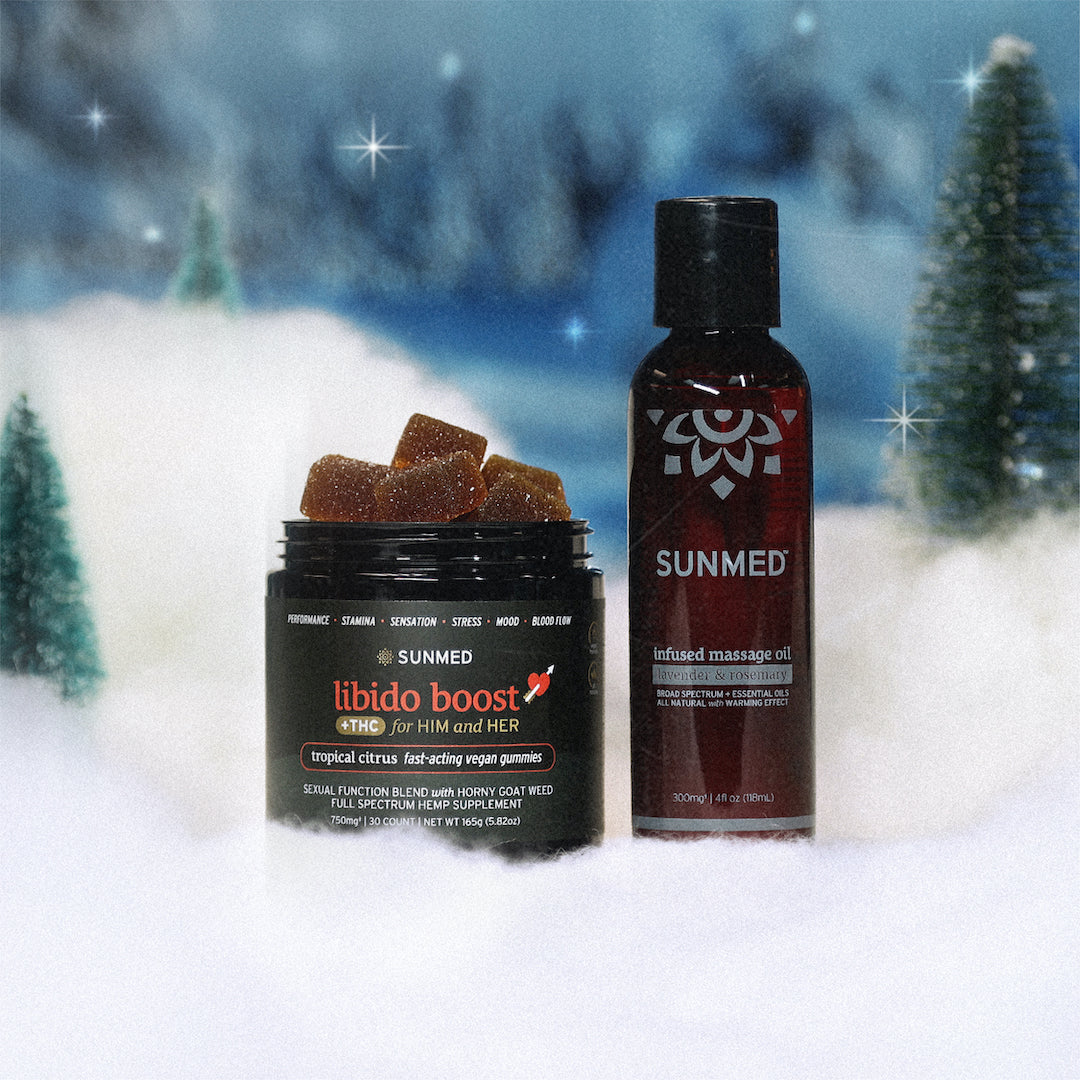 The Libido Gummies + Massage Oil Holiday Bundle by Sunmed CBD is displayed on a snowy surface, surrounded by small evergreen trees.