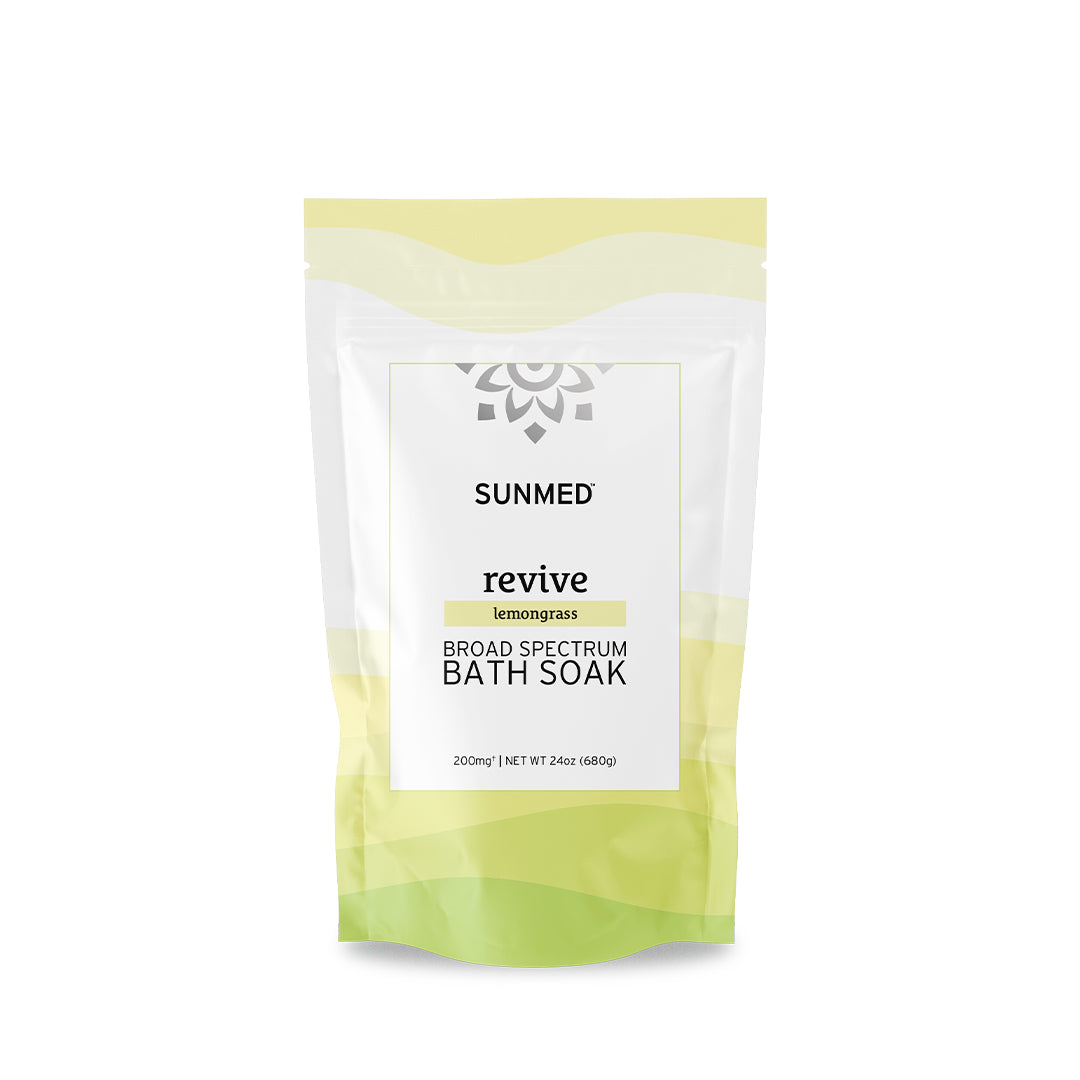 A white and green packet of Sunmed CBD Broad Spectrum Revive Lemongrass Bath Soak, infused with organic hemp and essential oils, containing 24 oz of product.