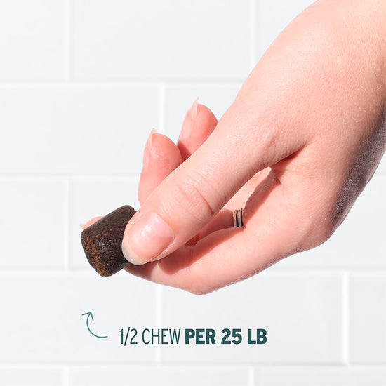 A hand holds a small, dark, chewable supplement. Text reads: 