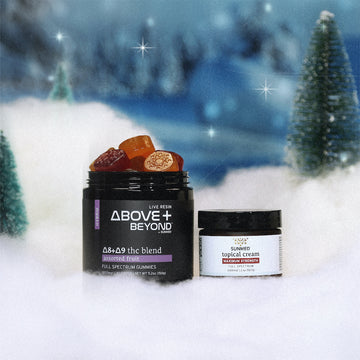 ABOVE + BEYOND Gummies and Topical Cream Holiday Bundle by Sunmed CBD showcased in a snowy setting with small pine trees in the background.