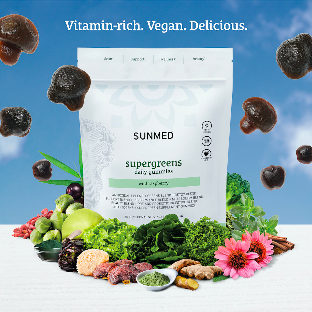 A bag of Sunmed CBD Supergreens Daily Gummies with wild raspberry flavor, surrounded by various greens, plants, and adaptogenic mushrooms against a blue sky background.