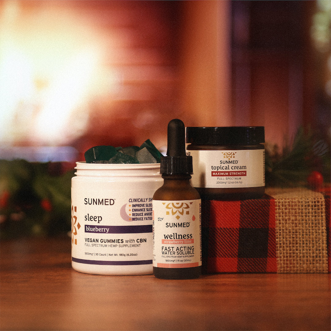 Sunmed CBD's Sleep Gummies + Water Soluble + Topical Cream Holiday Bundle displayed on a table with holiday decorations.