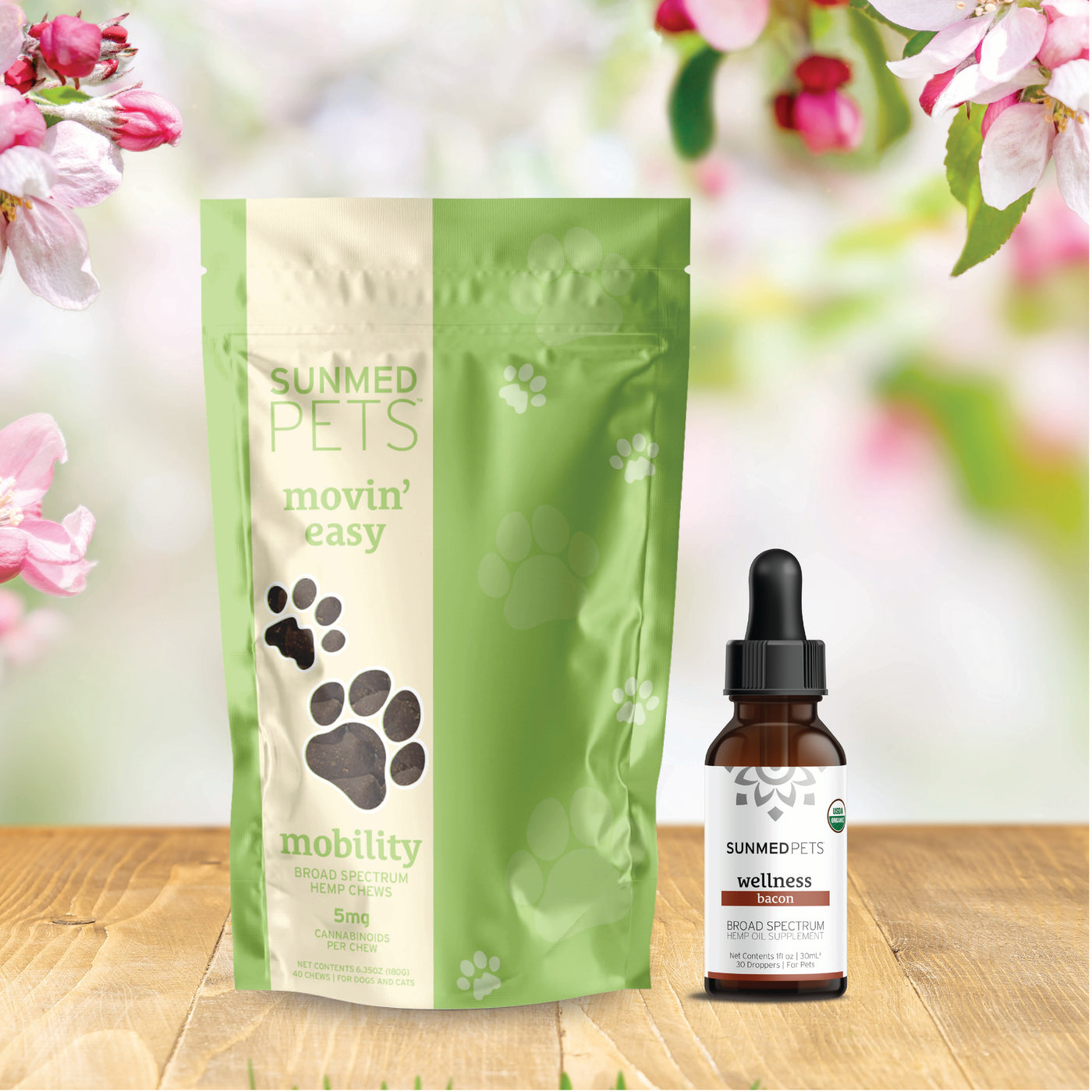 A green bag and dropper bottle from the Sunmed CBD Movin' Easy Pet Chews + Pet Tincture Bundle are displayed against a floral background.