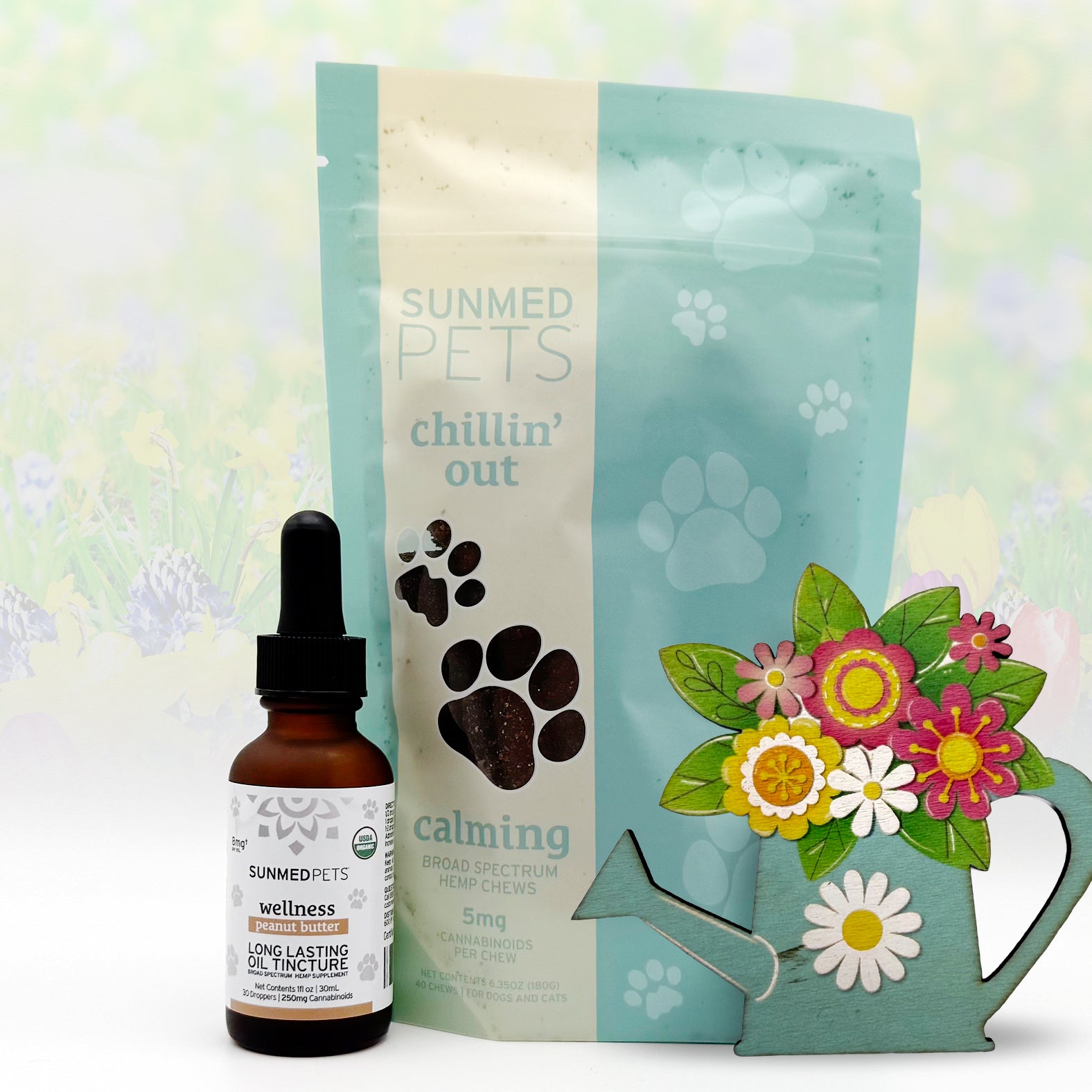 A Sunmed CBD Chillin' Out Pet Chews + Pet Tincture Bundle rests by a floral watering can, providing natural anxiety relief for pets.