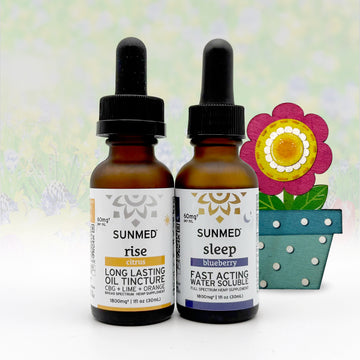 Two Sunmed CBD Full Spectrum Sleep + Rise Tincture bottles with droppers are positioned next to a vibrant decorative flower in a blue pot, highlighting this bundle’s sleep and wellness support.