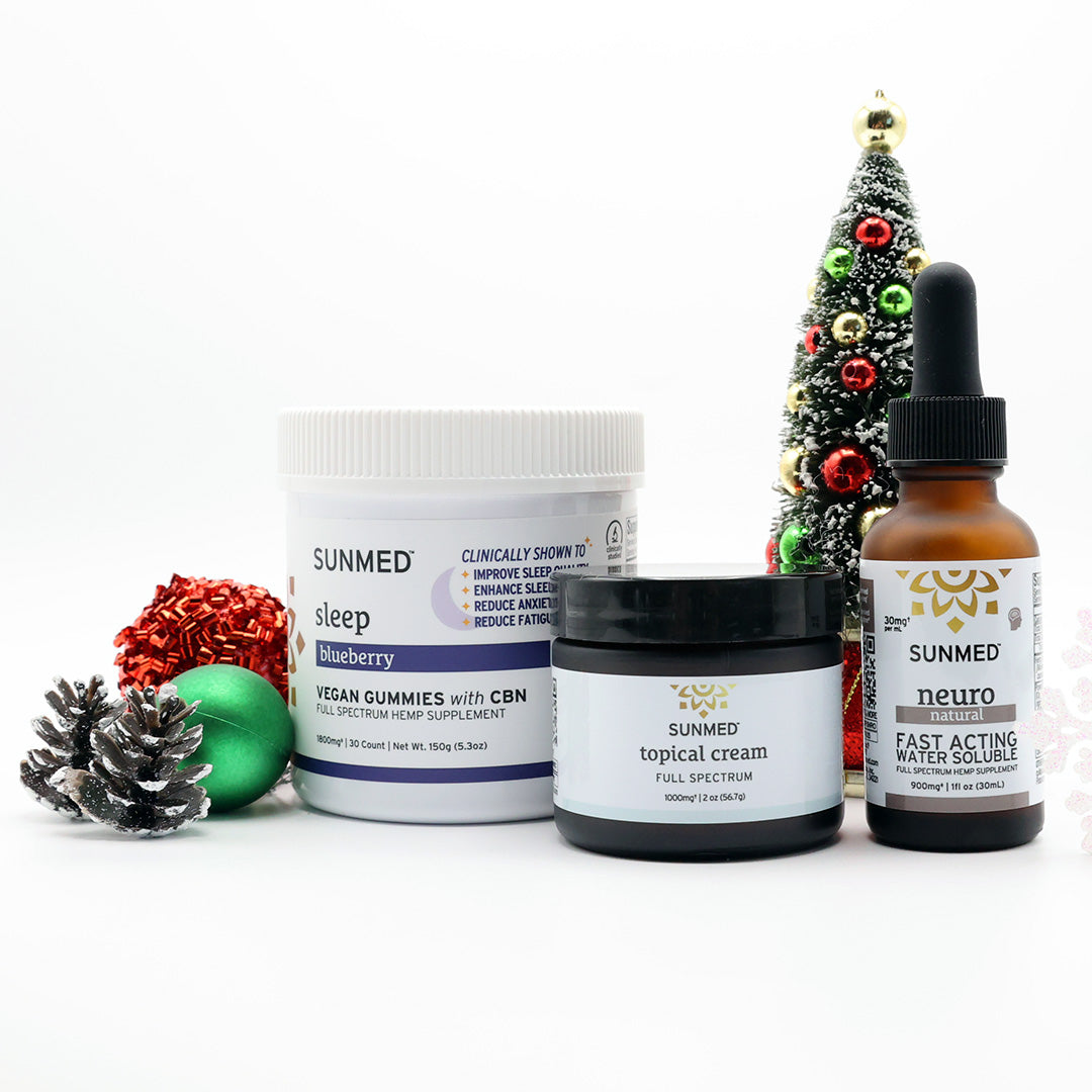 The Sunmed CBD Full Spectrum Sleep Gummies + Neuro Water Soluble + Topical Cream Bundle is shown beside holiday décor and a small Christmas tree on a white background, ideal for festive-season relaxation and restful sleep.