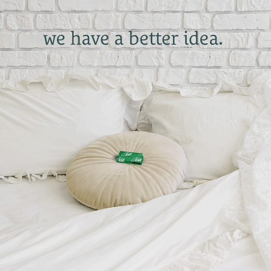A white bed with white pillows, a beige round pillow, and a mint on top, with text 